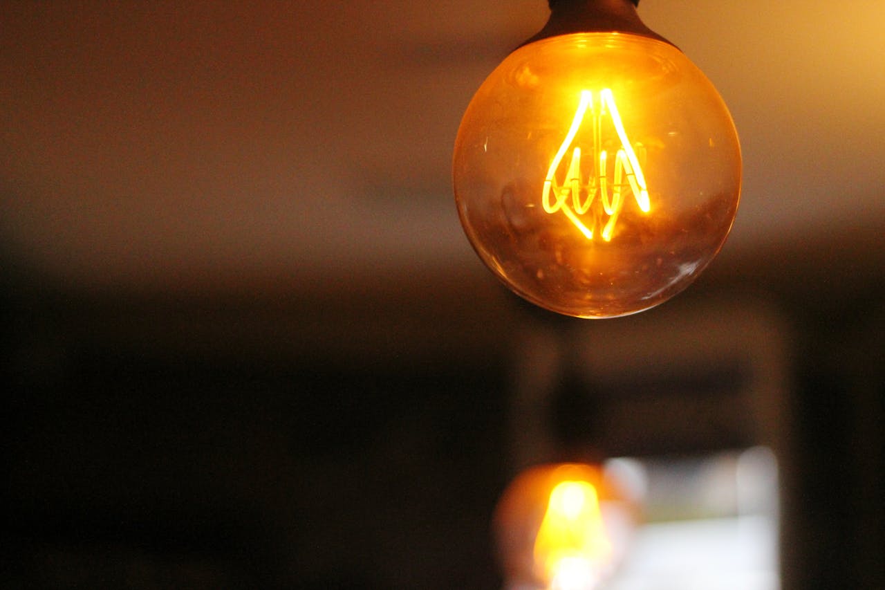 Warm, glowing vintage light bulb set against a blurred indoor background.